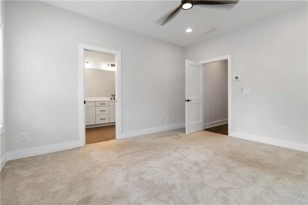Unfurnished bedroom featuring carpet floors, ensuite bath, recessed lighting, and ceiling fan