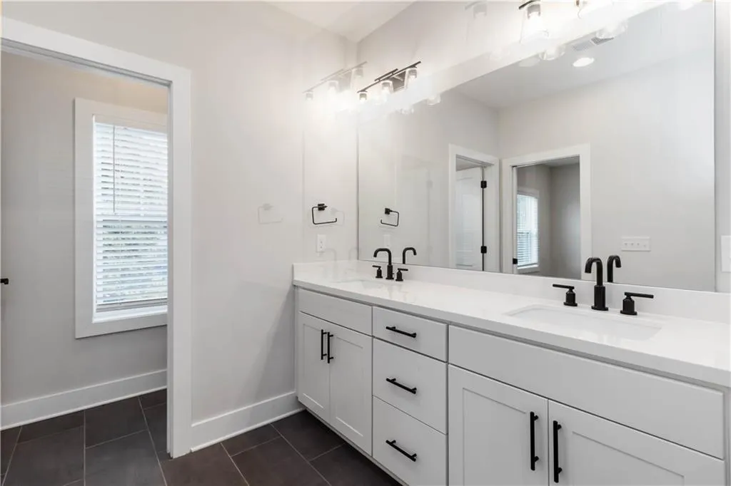 Full bathroom featuring double vanity, plenty of natural light, and tile patterned floors