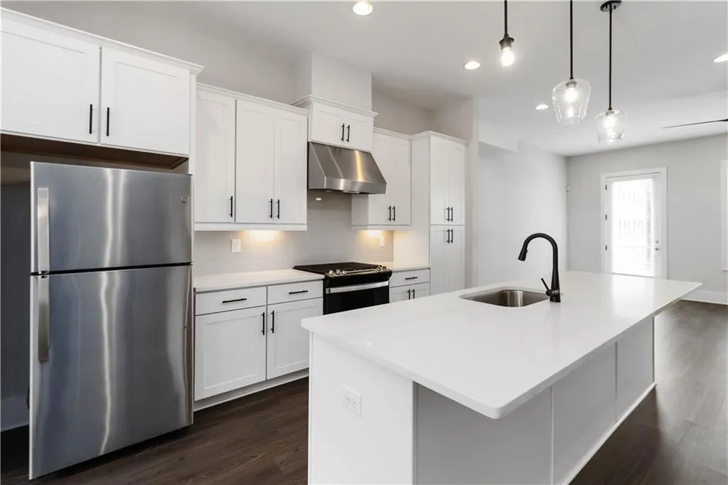 Kitchen featuring freestanding refrigerator, gas range, under cabinet range hood, dark wood-style floors, and recessed lighting