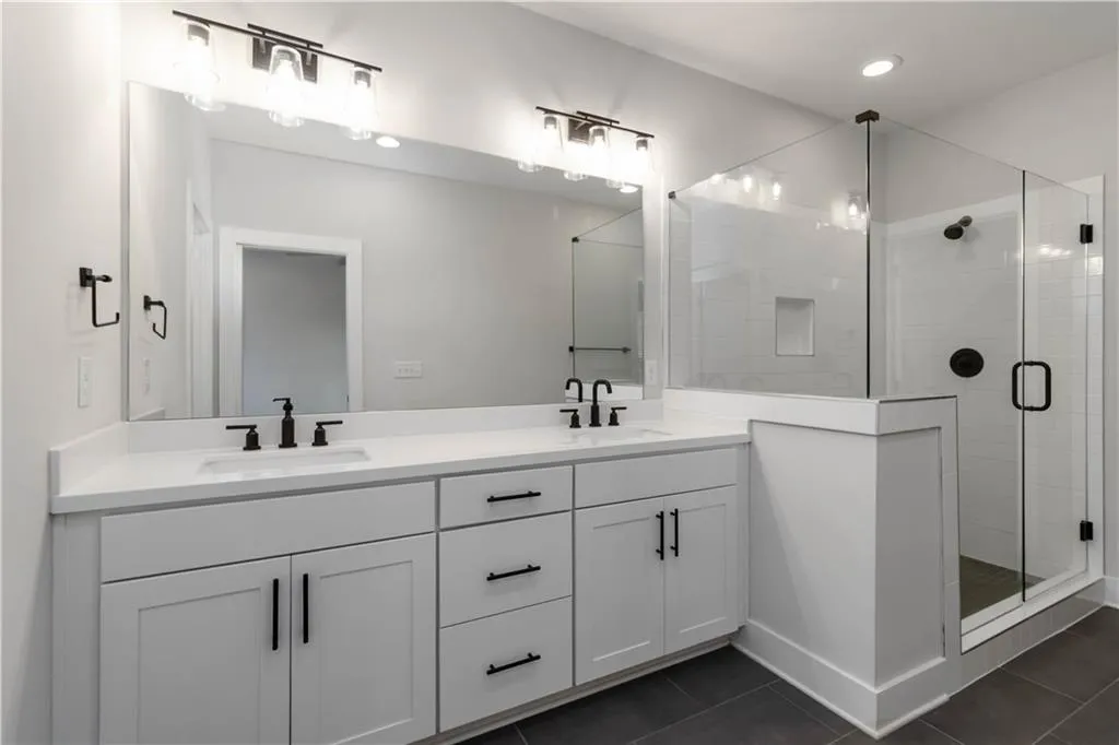 Full bathroom with tile patterned floors, double vanity, and a shower stall