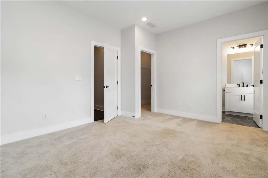 Unfurnished bedroom featuring carpet flooring, a spacious closet, connected bathroom, and recessed lighting