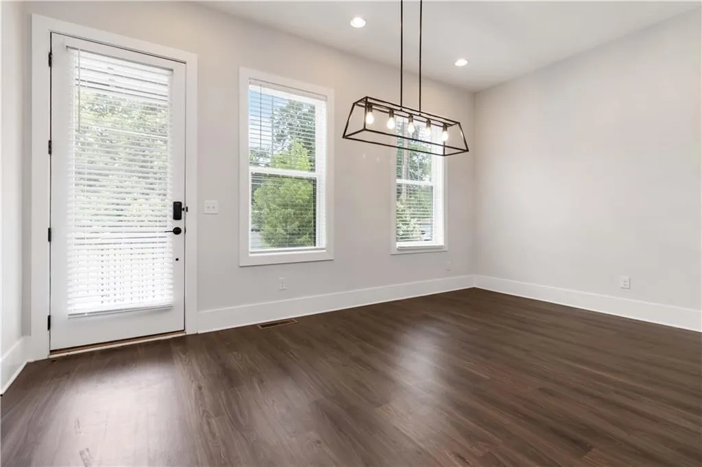 Unfurnished dining area with a chandelier, dark wood-type flooring, and recessed lighting