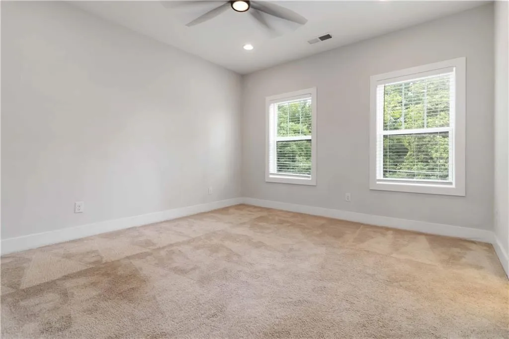 Carpeted empty room with ceiling fan and recessed lighting