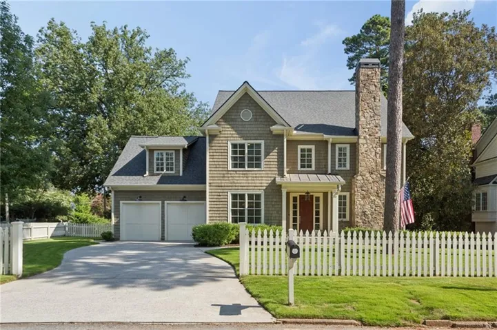 Shingle-sided exterior with a stone chimney, a gabled roofline, and a prominent front entrance