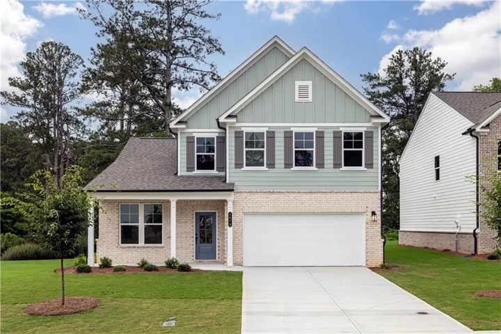 Two-story residence featuring a partial brick facade, horizontal siding, architectural shingles, an attached garage, and a covered front entry