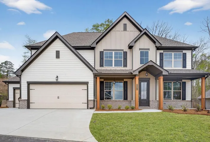 Craftsman house featuring brick siding, a front yard, covered porch, and board and batten siding