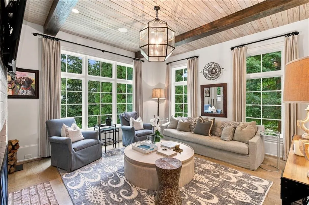 Cozy fireside living room with beamed ceiling opens to covered porch.