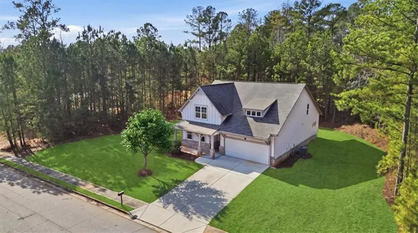 Contemporary exterior with white siding and dark roof, attached garage, covered front porch, and mature trees surrounding the property