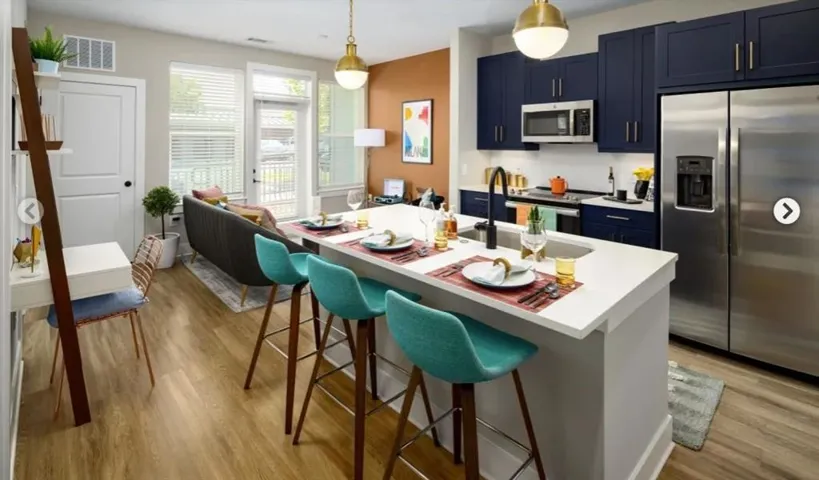 Kitchen with appliances with stainless steel finishes, a breakfast bar area, a kitchen island with sink, and light hardwood / wood-style floors