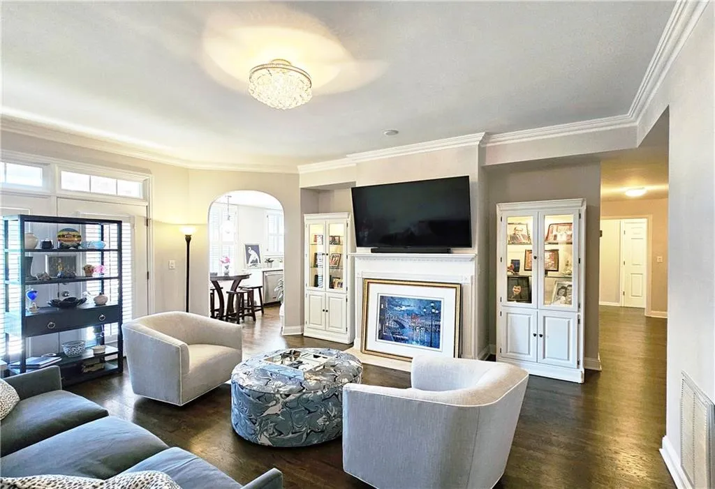 Living room featuring arched walkways, ornamental molding, and dark wood-type flooring
