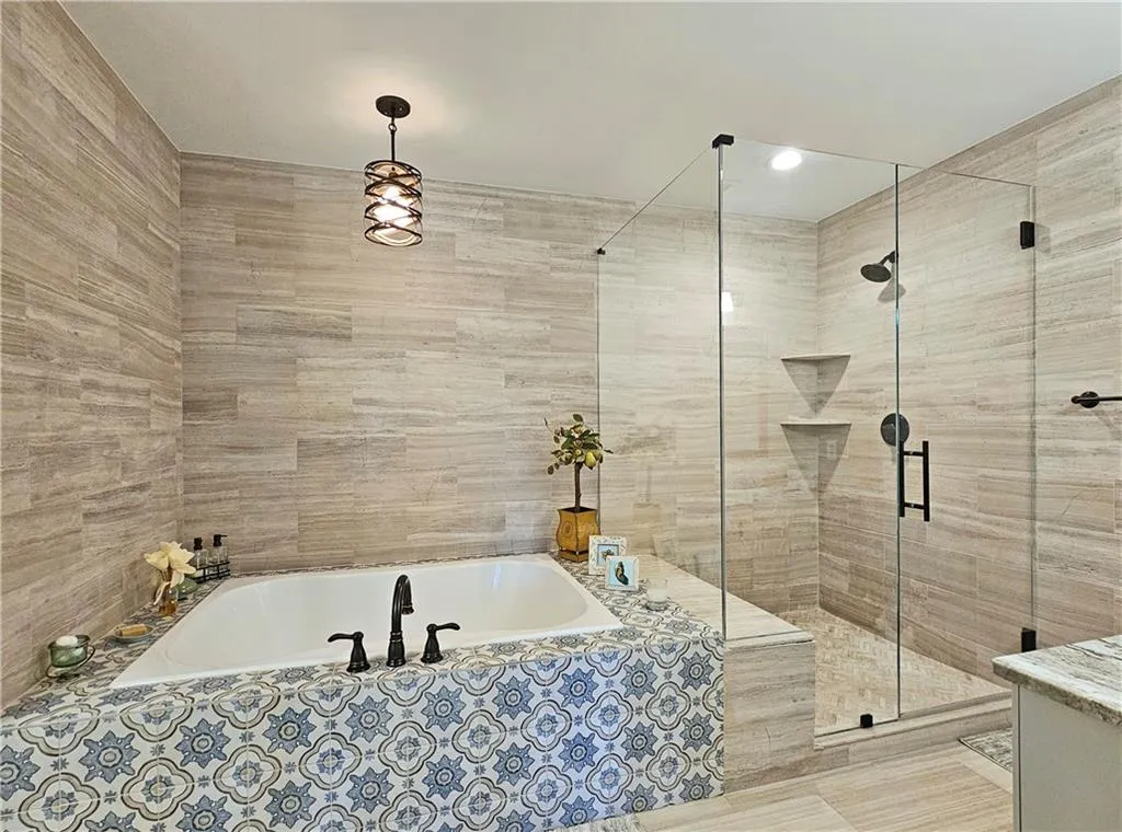 Full bath with tile walls, a bath, and a shower stall