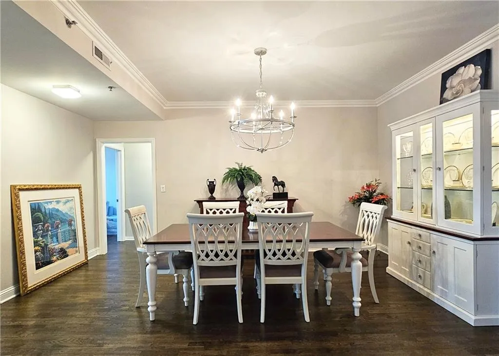 Dining room with a chandelier, dark wood-style floors, and ornamental molding