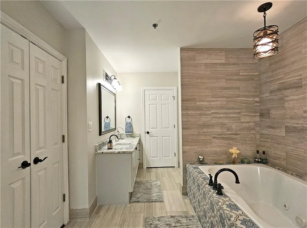Full bathroom featuring vanity, a whirlpool tub, and a closet