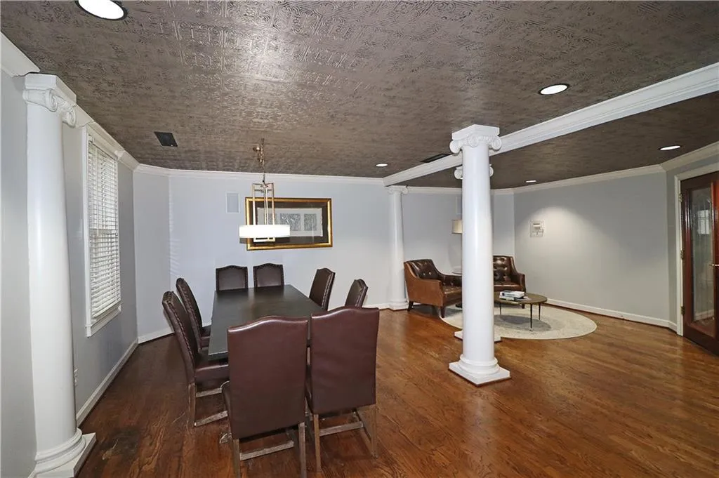 Dining area featuring ornate columns, wood finished floors, crown molding, and recessed lighting