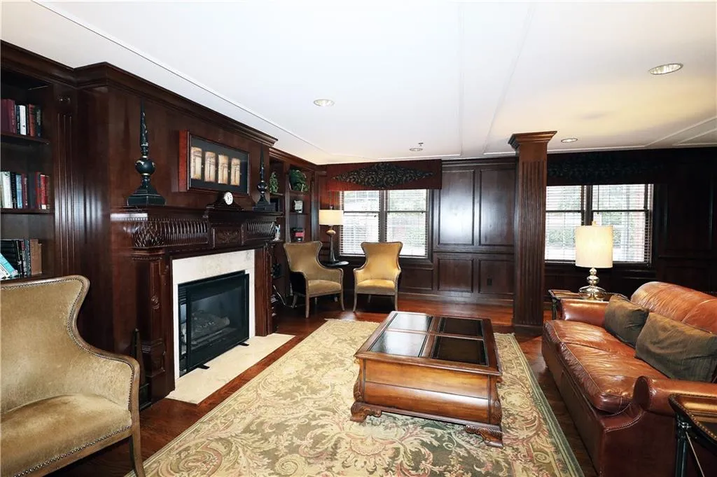 Living area featuring a fireplace, wood finished floors, and ornate columns
