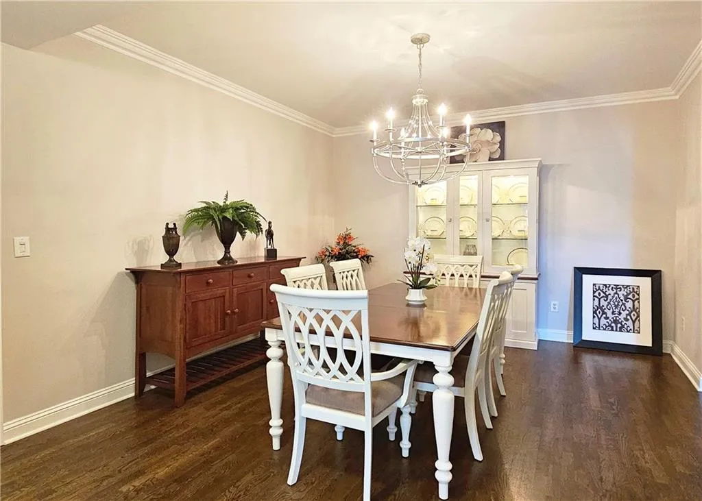 Dining space with a chandelier, dark wood-style floors, and ornamental molding