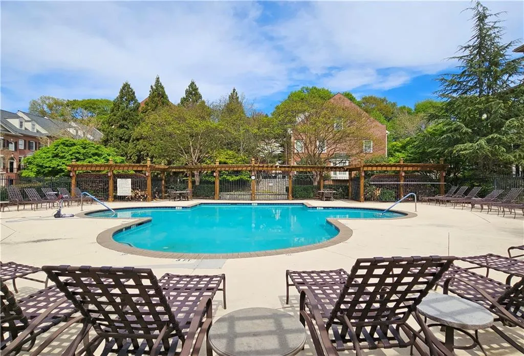 Community pool with a patio and view of wooded area