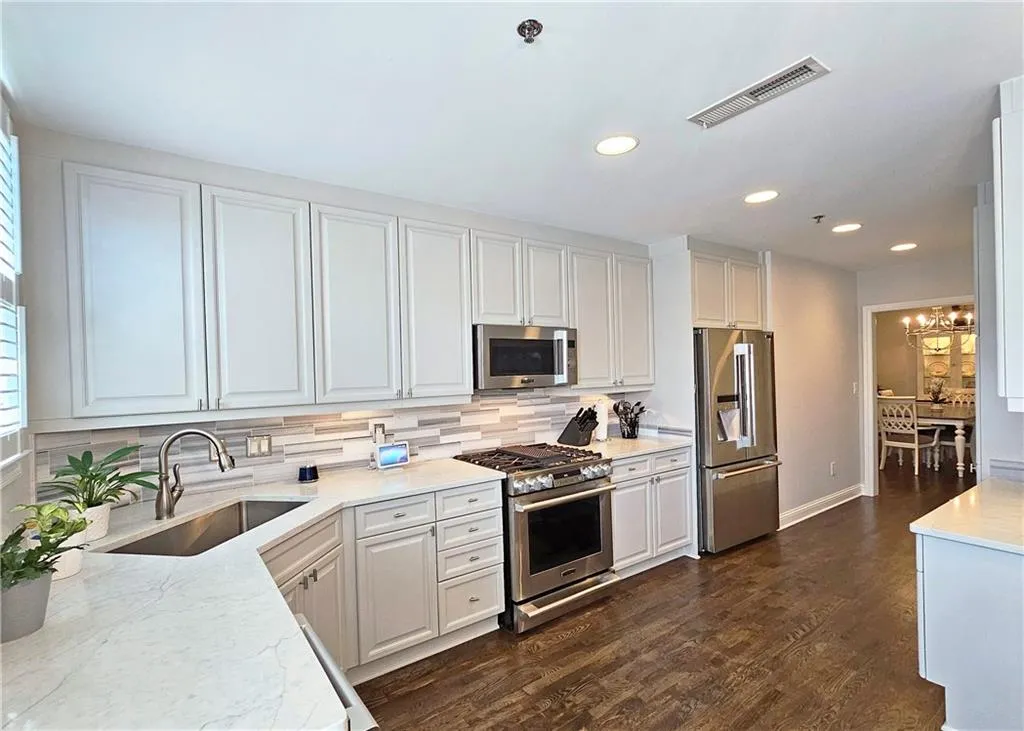Kitchen featuring stainless steel appliances, tasteful backsplash, recessed lighting, white cabinets, and a chandelier