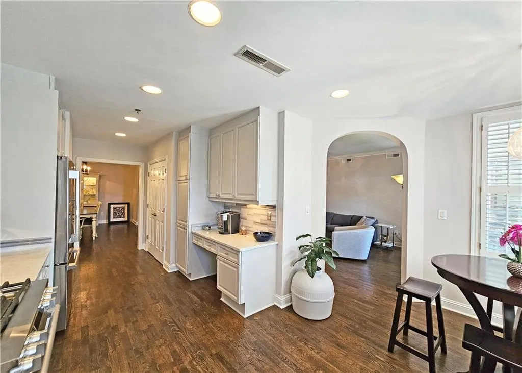 Kitchen with arched walkways, light countertops, appliances with stainless steel finishes, dark wood-style flooring, and recessed lighting