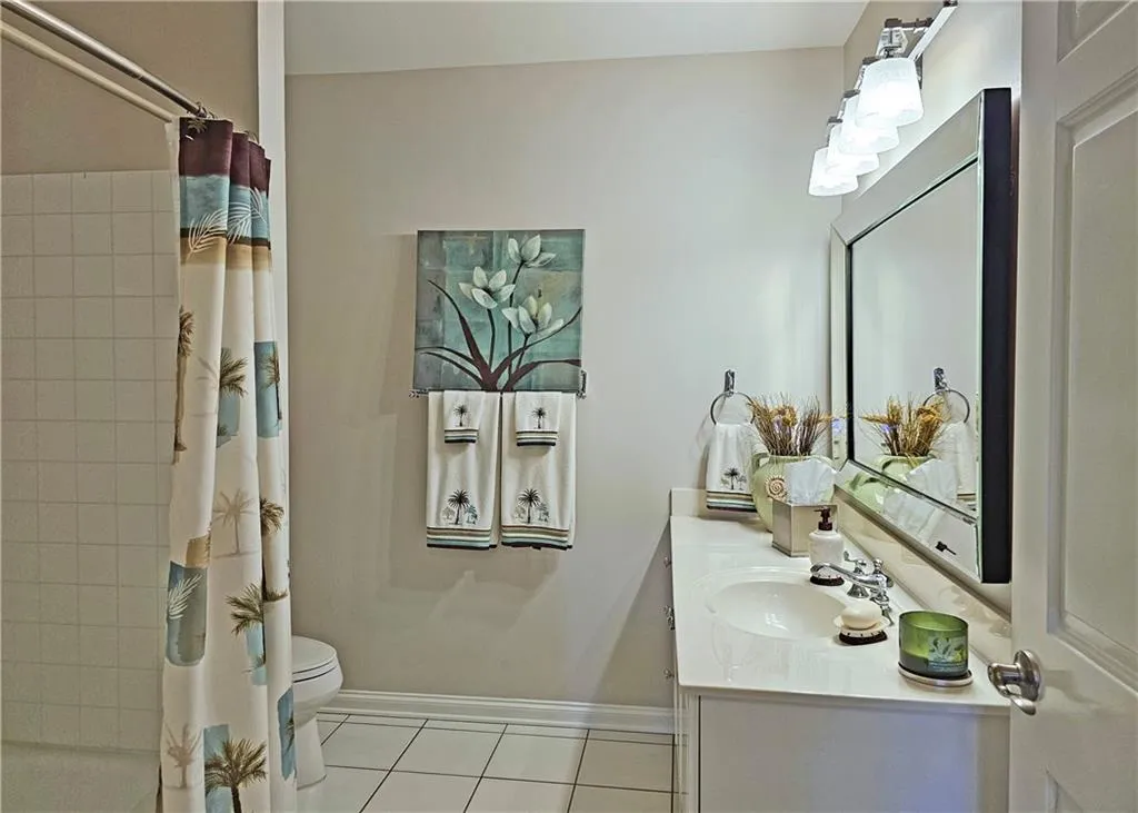 Bathroom featuring tile patterned floors, vanity, and curtained shower
