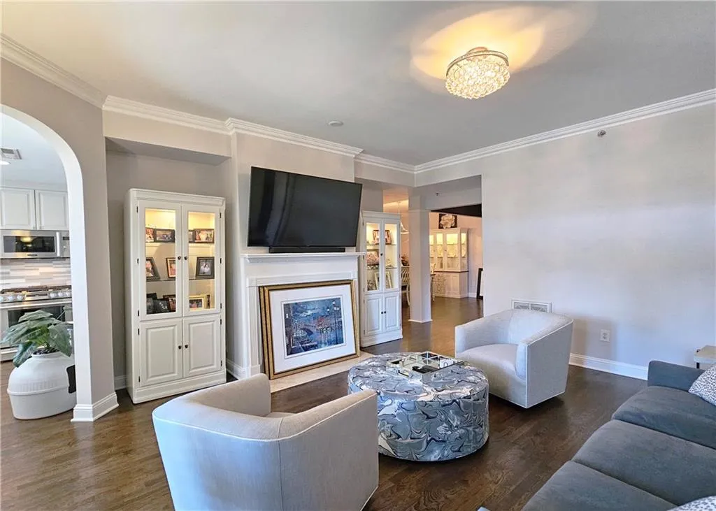 Living area with dark wood finished floors, crown molding, and arched walkways