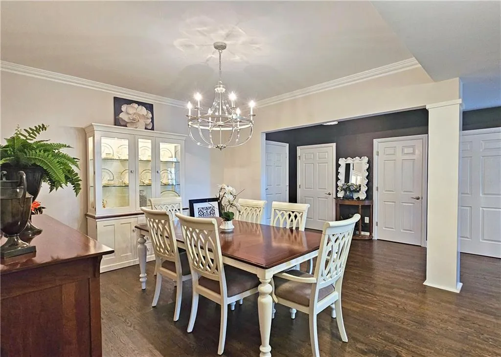 Dining space with a chandelier, dark wood-type flooring, and crown molding