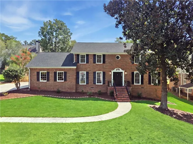 Brick exterior with black shutters and a dark shingle roof