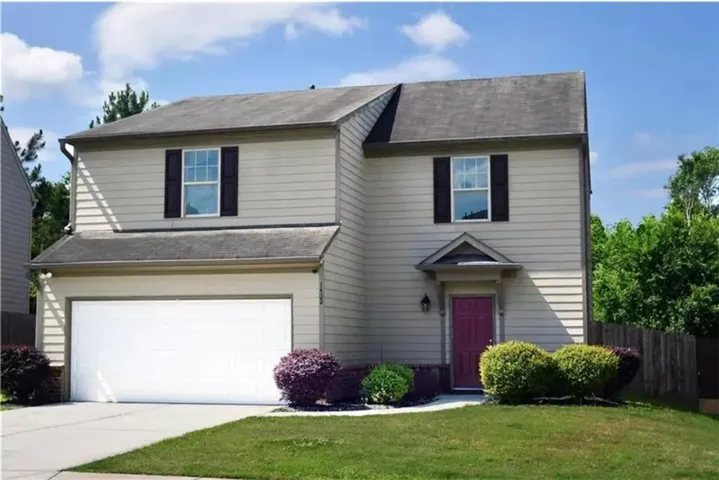 Two-story residence featuring light-colored siding, a white garage door, and a covered entryway with a contrasting front door