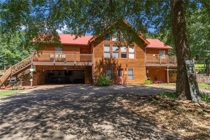 View of front facade featuring driveway, a metal roof, a wooden deck, and stairs