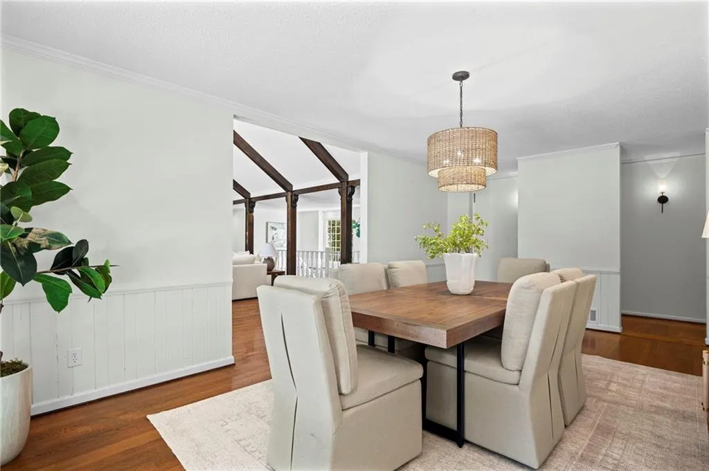 Dining room with wood finished floors, a wainscoted wall, ornamental molding, and a textured ceiling