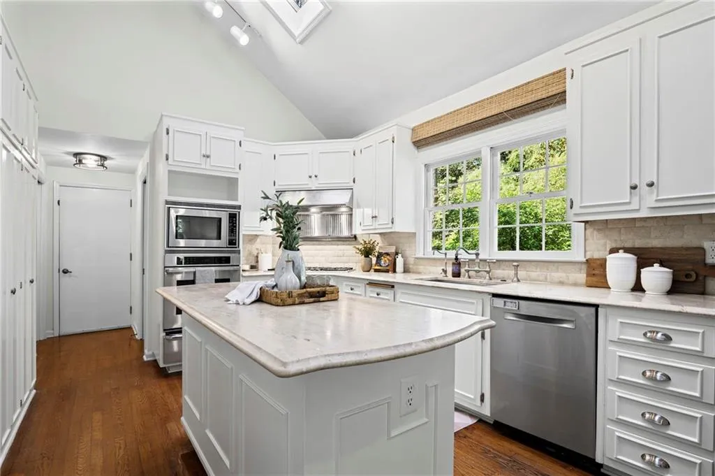 Stainless steel appliances include dishwasher, gas range and hood, integrated microwave, oven, and warming drawer