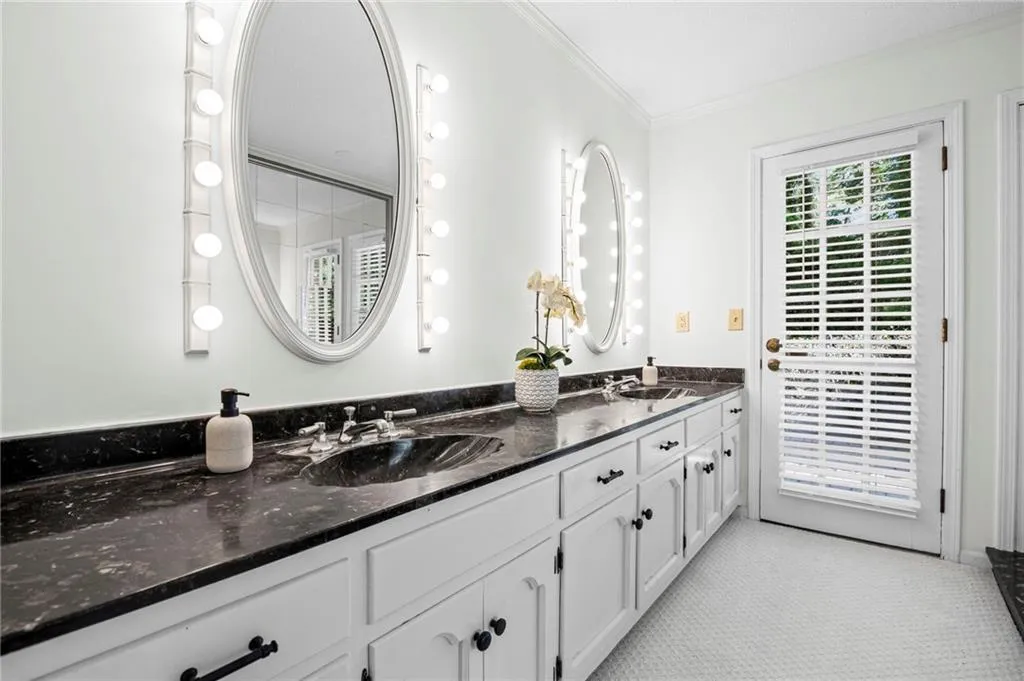 Primary Bathroom featuring double vanity and fresh paint. Exterior door leads to pool area.