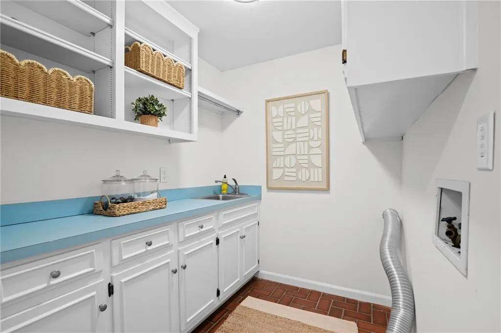 Laundry area featuring cabinet space and brick flooring