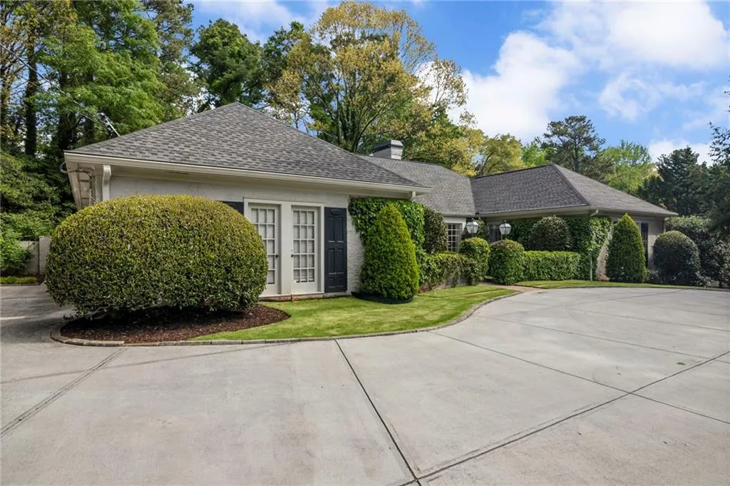 View of front facade featuring a chimney, roof with shingles, a front lawn, french doors, and concrete driveway