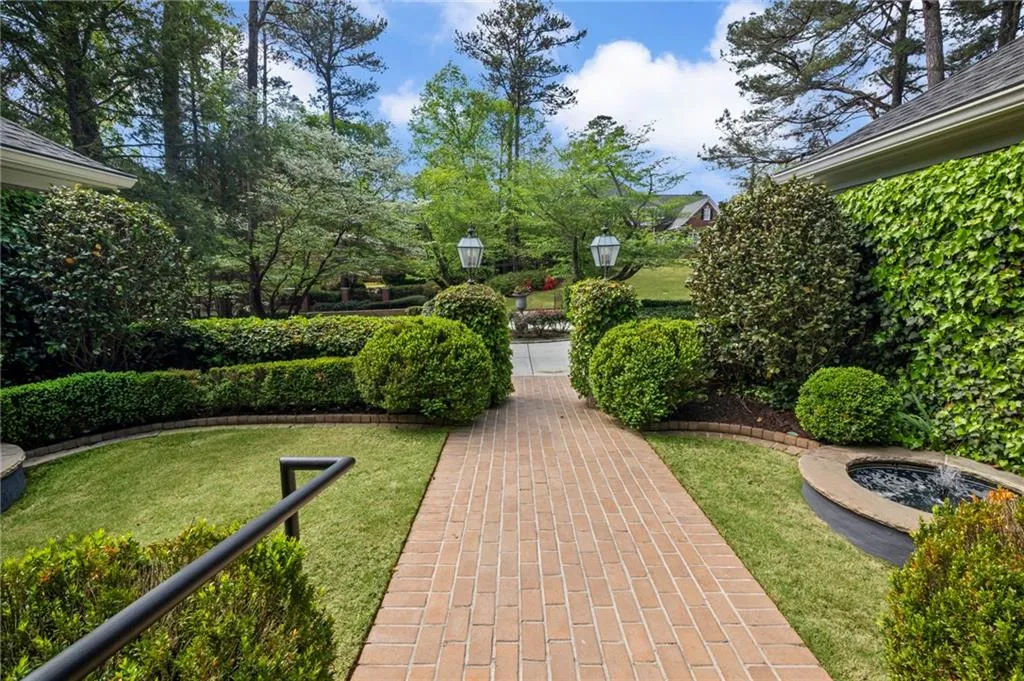 Meticulously maintained Courtyard entrance with brick path and accent, lanterns, and dual fountains