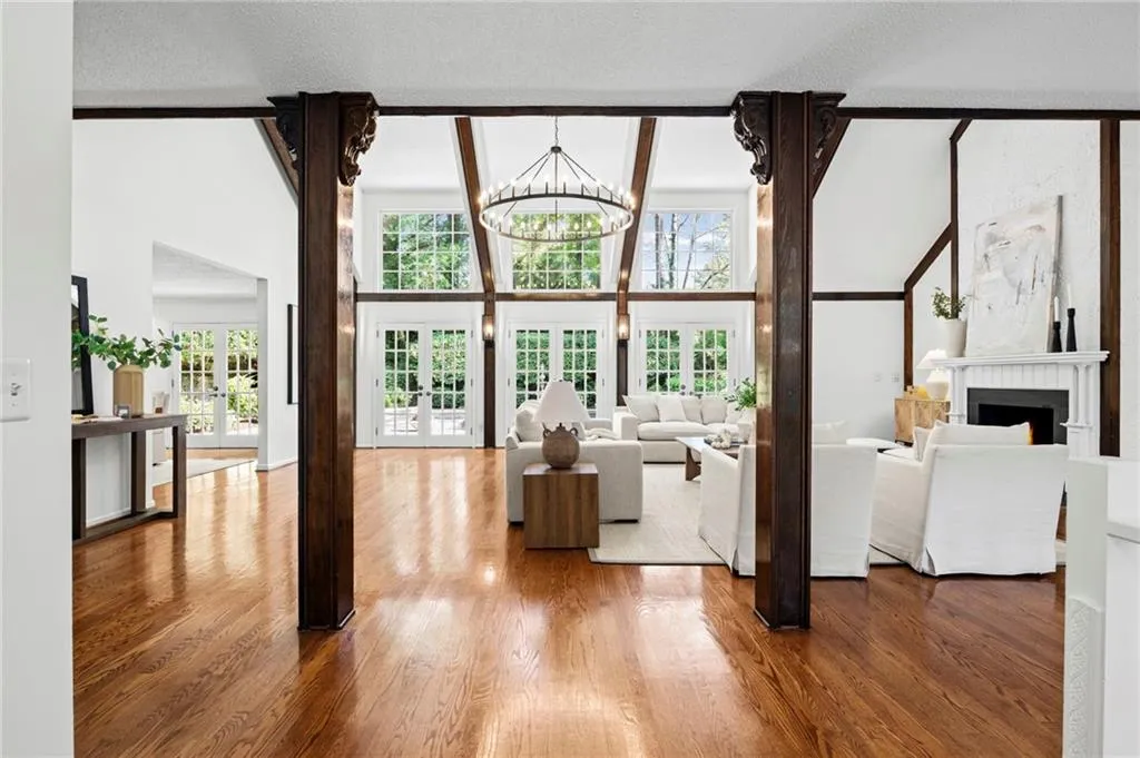Open foyer leads to Living area with french doors, a fireplace, hanging lights, hardwood flooring, and Cathedral Ceilings