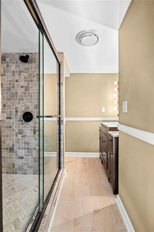 Lower level full bathroom with glass enclosed shower and vanity sink