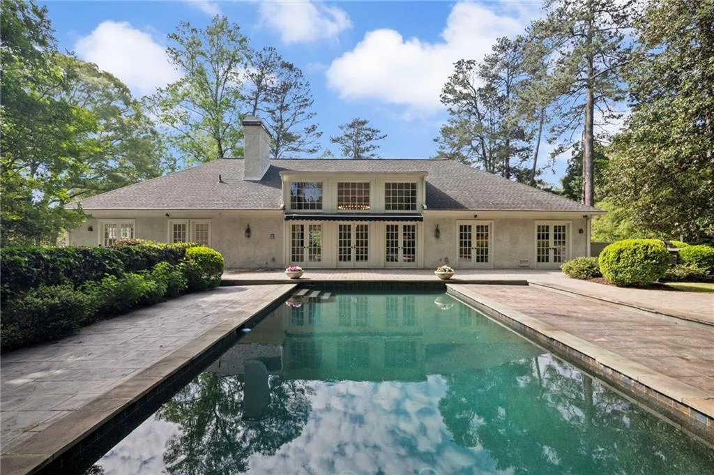 Rear view of property featuring french doors, a patio area, a chimney, and roof with shingles
