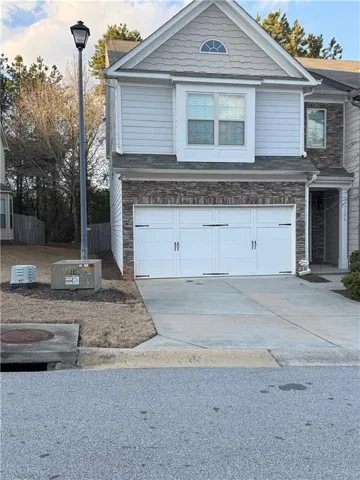 View of front of property featuring stone siding, a garage, and concrete driveway