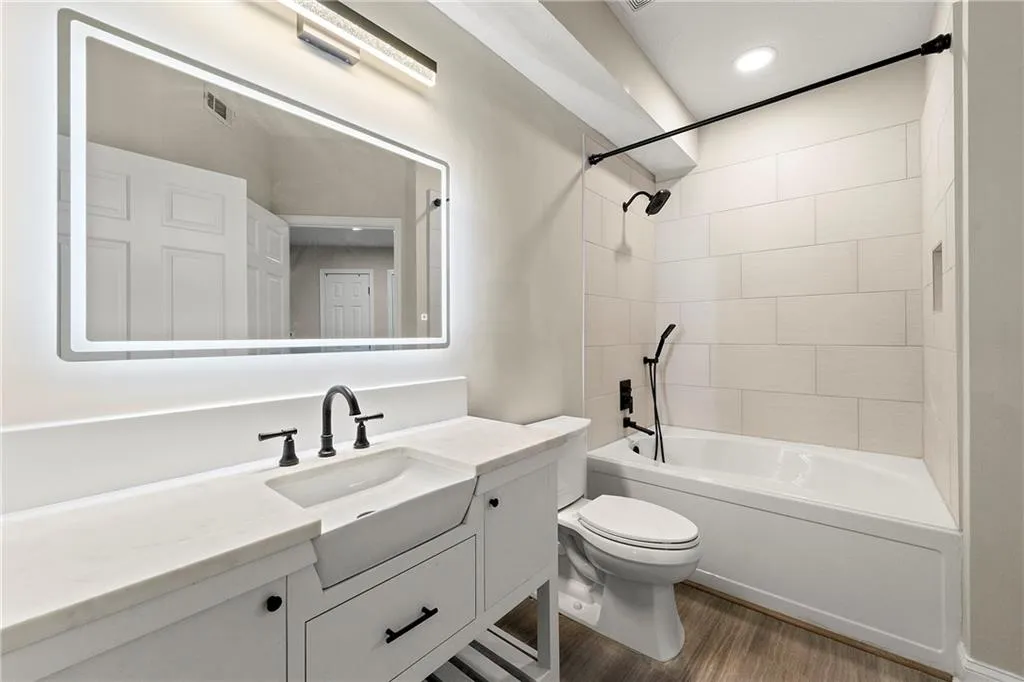 Full bathroom with tiled shower / bath, vanity, toilet, and wood-type flooring