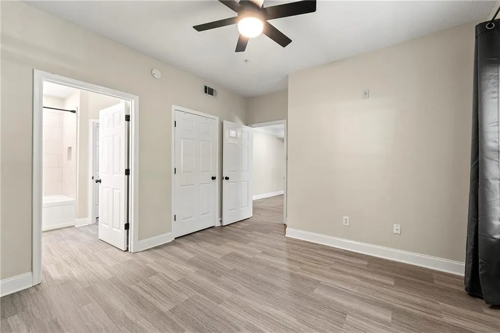Unfurnished bedroom with light hardwood / wood-style floors, connected bathroom, and ceiling fan