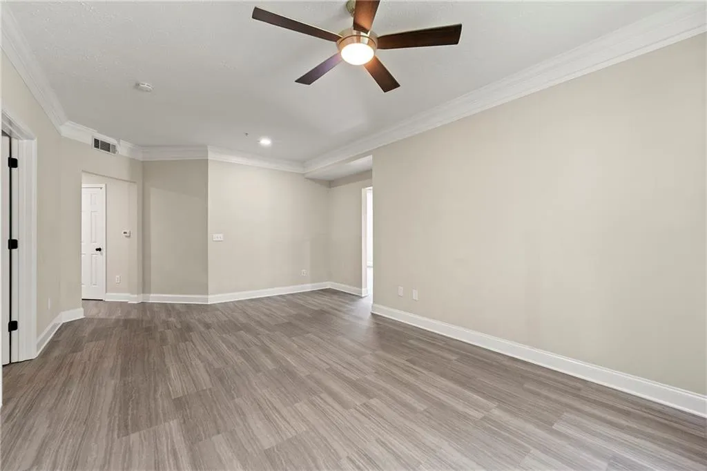 Empty room with ceiling fan, crown molding, and hardwood / wood-style flooring