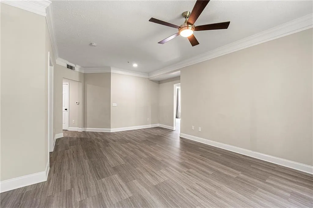 Empty room featuring crown molding, a textured ceiling, wood-type flooring, and ceiling fan