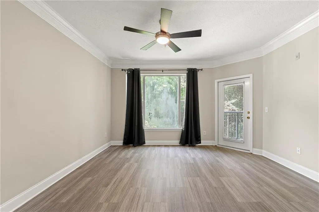 Unfurnished room featuring a textured ceiling, ornamental molding, light wood-type flooring, and ceiling fan