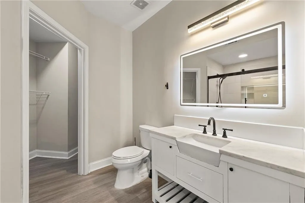 Bathroom featuring tiled shower, hardwood / wood-style flooring, toilet, and oversized vanity