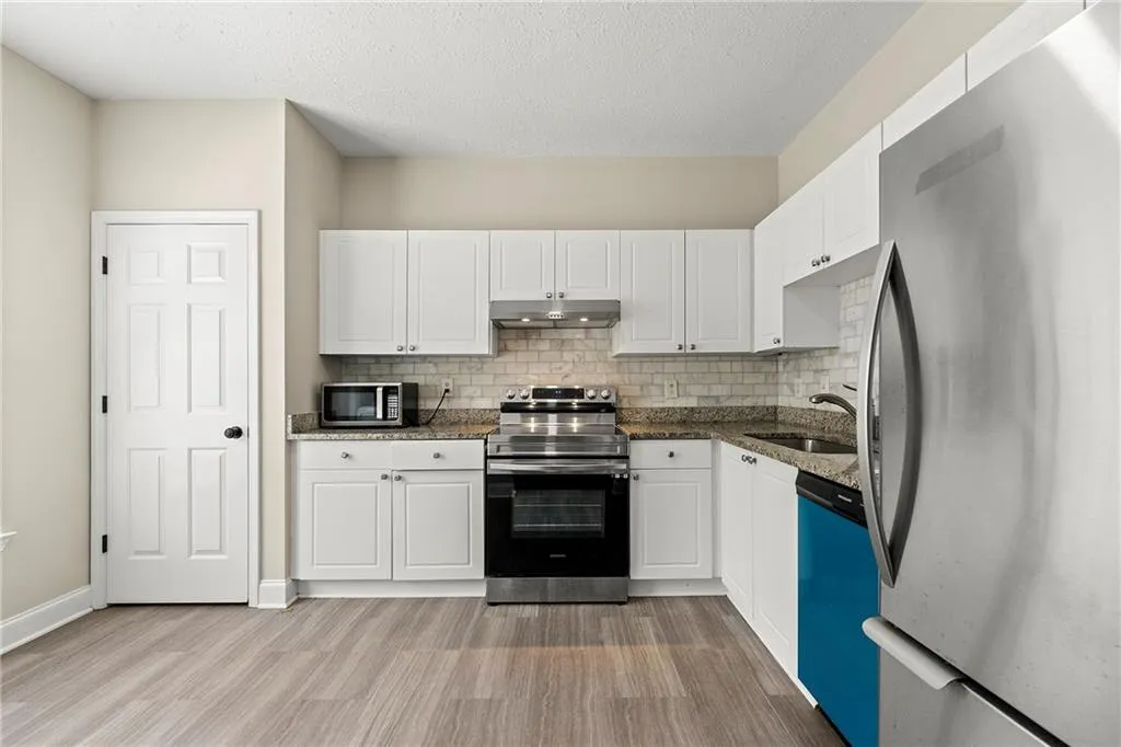 Kitchen with white cabinets, appliances with stainless steel finishes, sink, and light hardwood / wood-style flooring