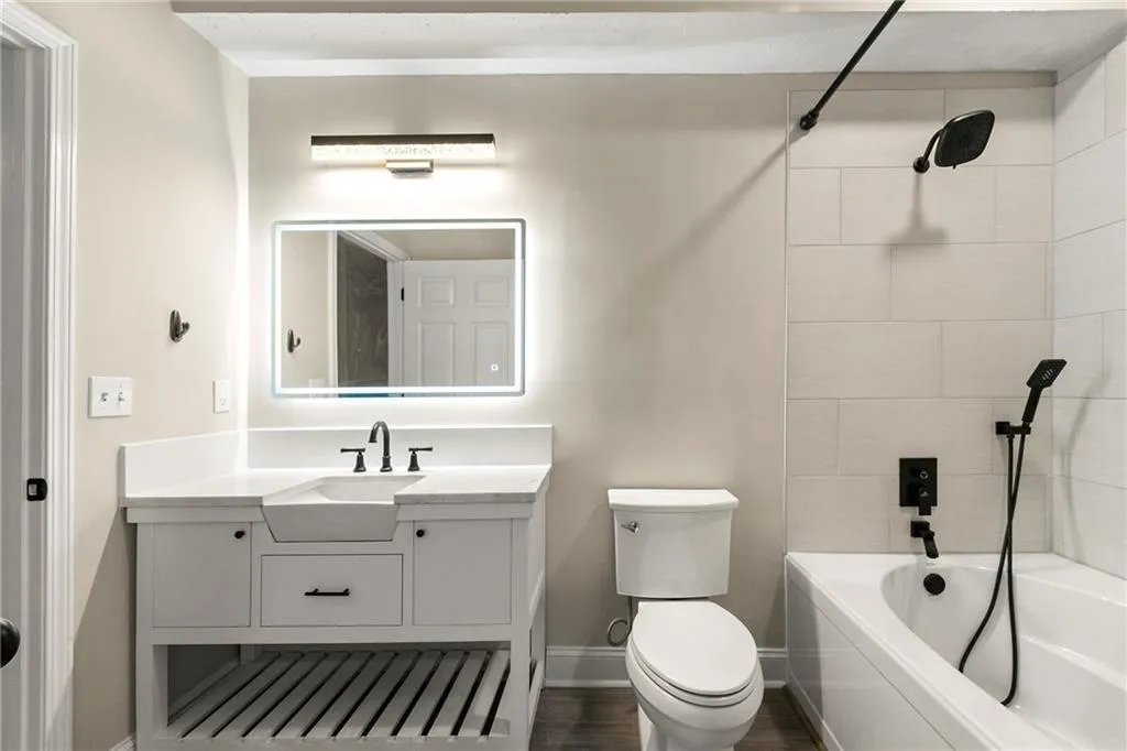 Full bathroom with tiled shower / bath, hardwood / wood-style floors, toilet, and vanity