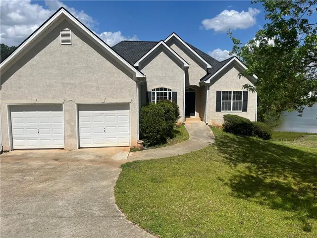 View of front of house featuring a front yard, stucco siding, a garage, and concrete driveway