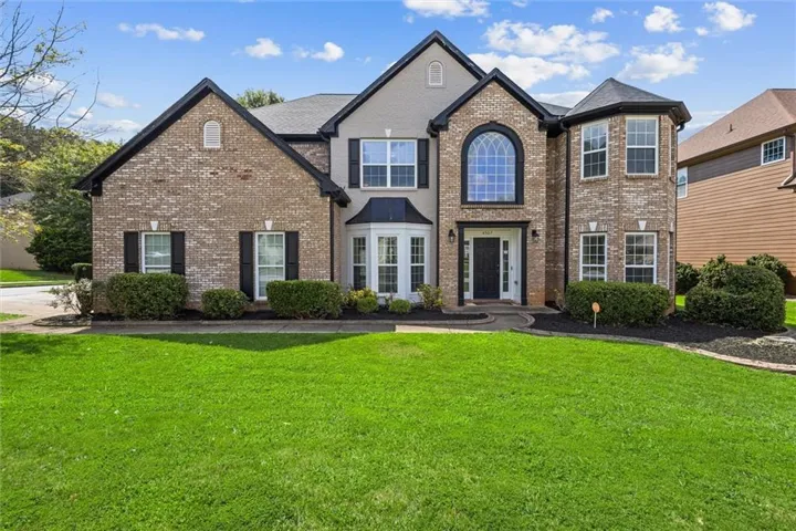 Brick facade with architectural turret, decorative arched window, bay window, and dark contrasting trim