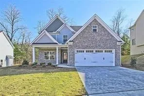 Distinguished home featuring a two-car garage, brick and siding exterior, covered front porch with columns, and a paved driveway
